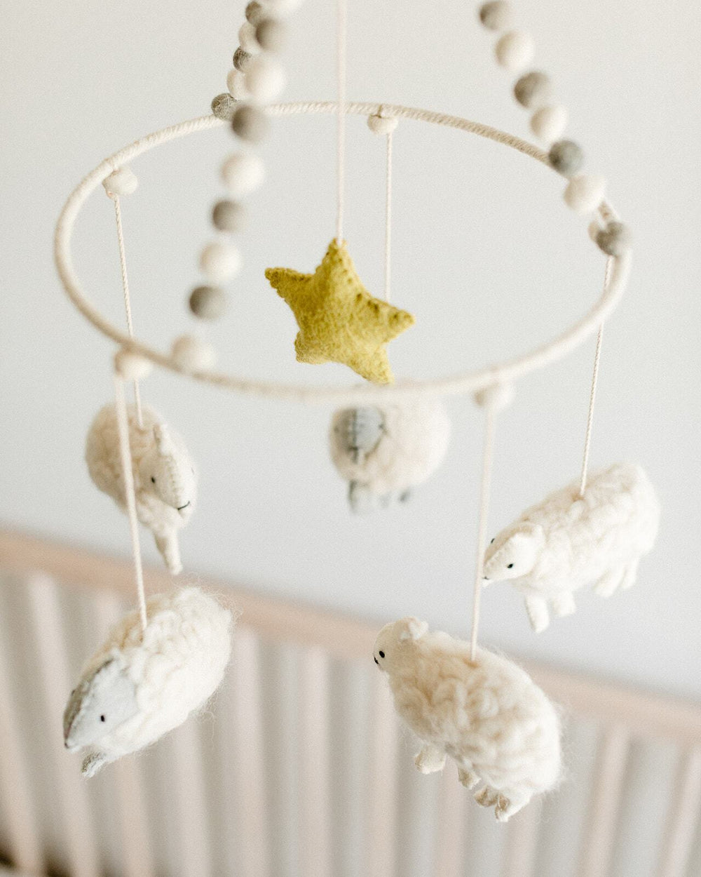 Close up of Pehr Counting Sheep Classic Mobile in nursery. Ethically Handmade using 100% wool and AZO-Free dyes. Mobile with Sheep.