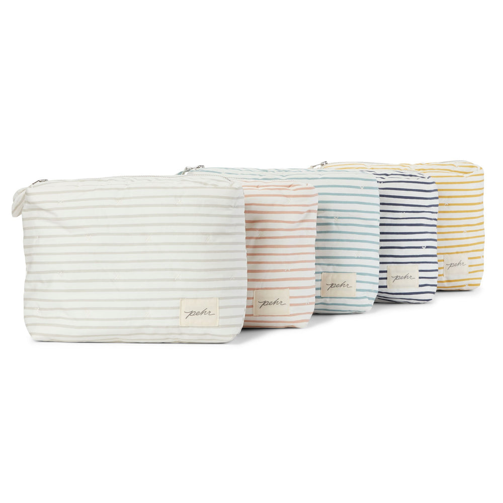 All of the Pehr Organic On The Go Travel Pouches in Rose Pink, Deep Sea, Pebble, Ink Blue, and Marigold stacked on top of each other. GOTS Certified Organic Cotton & Dyes.