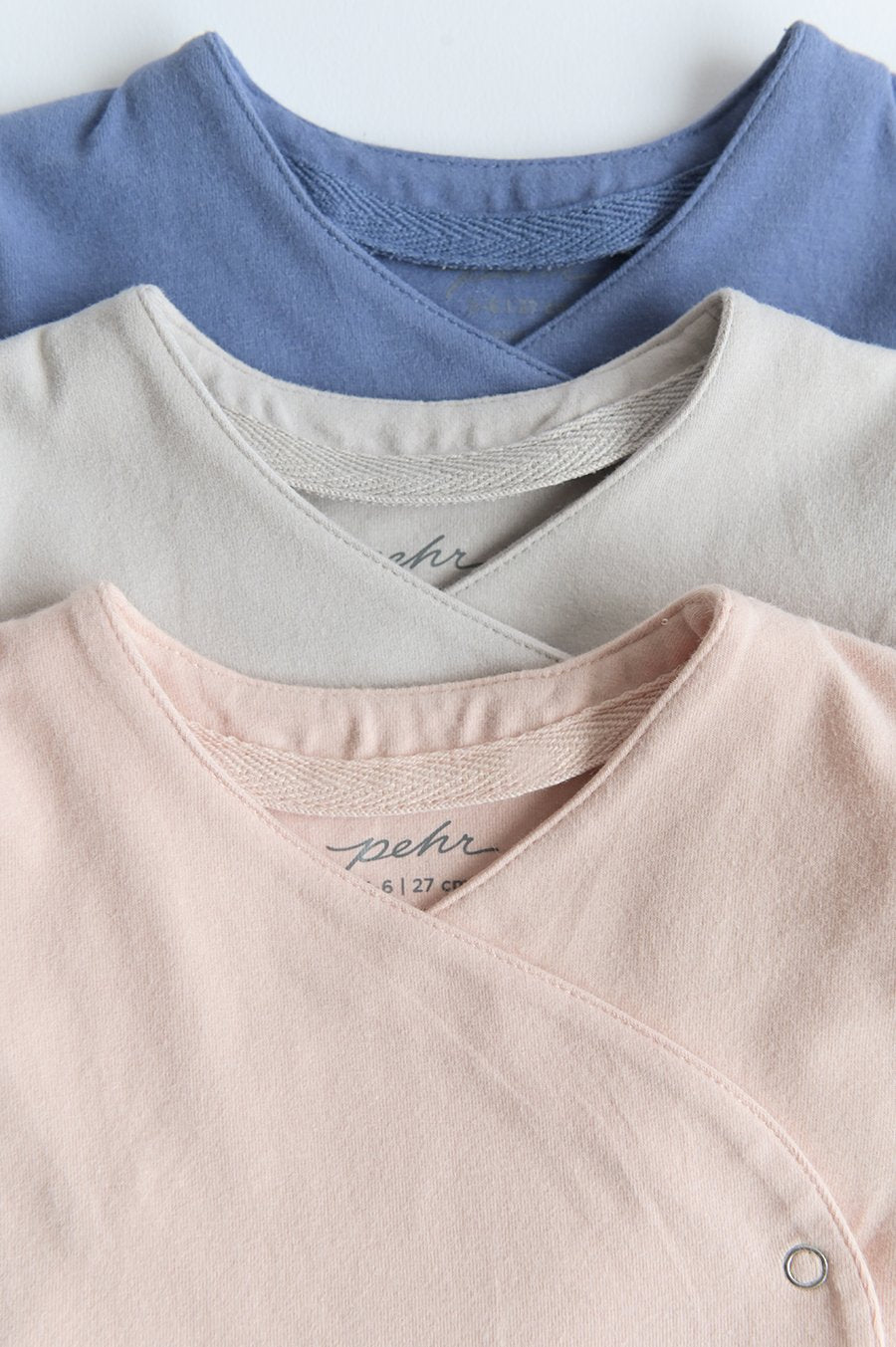 Pehr Essentials Wrap Cardigans in Powder Pink, Dove Grey, and Cloud blue layered on top of each other. GOTS Certified Organic Cotton & Dyes.
