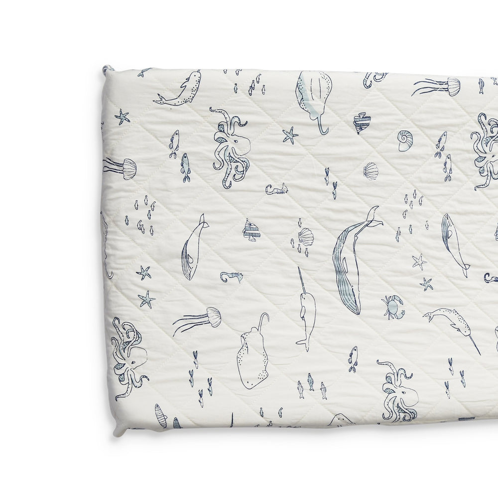 Close up of Pehr Life Aquatic Change Pad Cover. Hand printed. White with navy blue sea creatures in line drawing print.