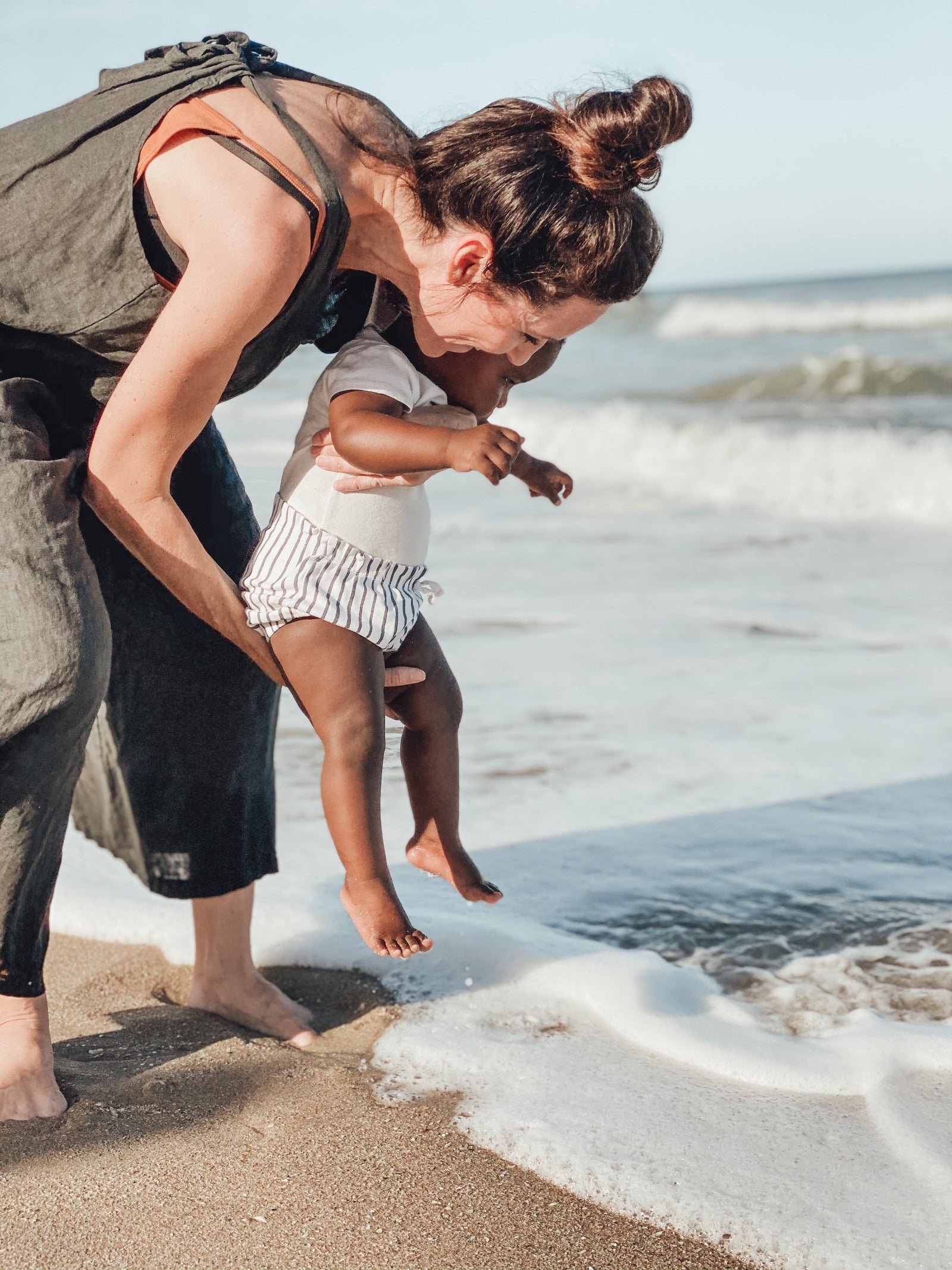 Baby on beach with mom wearing Pehr Stripes Away Bloomers in Ink Blue. Organic shorts white with ink blue stripes.