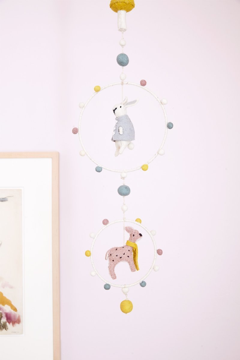 Pehr Magical Forest Hoop Mobile hanging above crib in nursery. Hand made. 100% wool. Rabbit and deer hanging in hoops with coloured pom poms.
