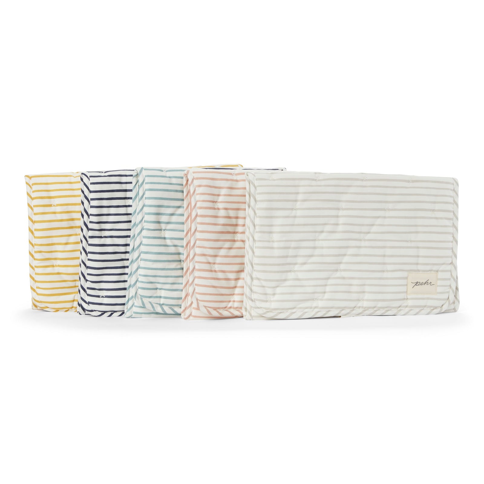 All of the Pehr Organic On The Go Travel Change Pads in Rose Pink, Deep Sea, Pebble, Marigold, and Ink Blue layered on top of each other. GOTS Certified Organic Cotton & Dyes.