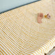 Pehr Stripes Away Marigold Change Pad Cover with comb and pacifier on top. Hand printed. White with gold stripes.