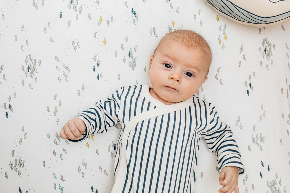 Baby wearing Pehr Stripes Away Ink Blue Organic Kimono One-Piece, Long Sleeve. GOTS Certified Organic Cotton & Dyes. White with dark blue stripes.