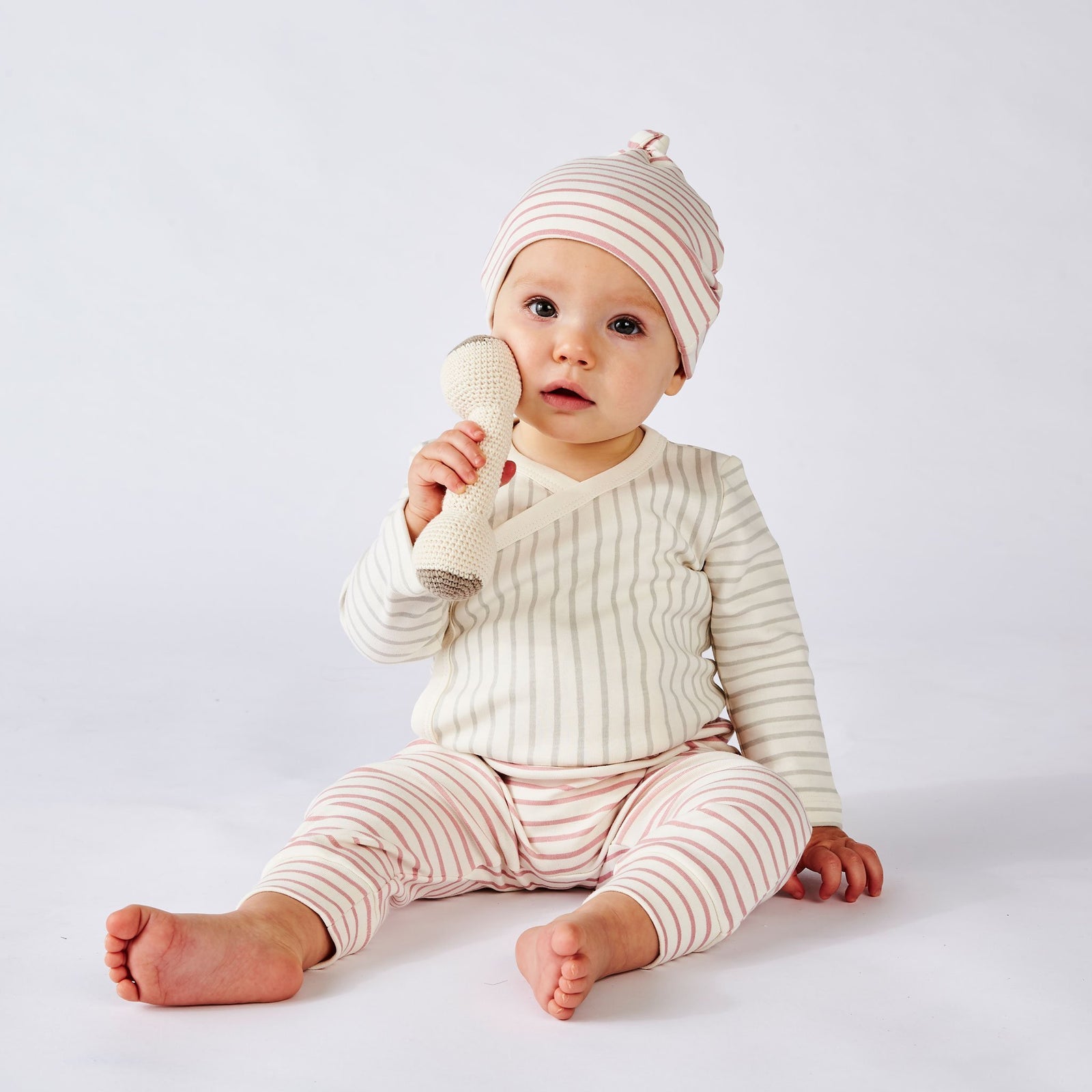 Baby wearing Pehr Stripes Away Dark Pink Organic Knot Hat, Pehr Stripes Away Pebble Grey Organic Kimono One-Piece, Long Sleeve, and Pehr Dark Pink Organic Harem Pant. GOTS Certified Organic Cotton & Dyes. White with dark pink stripes.