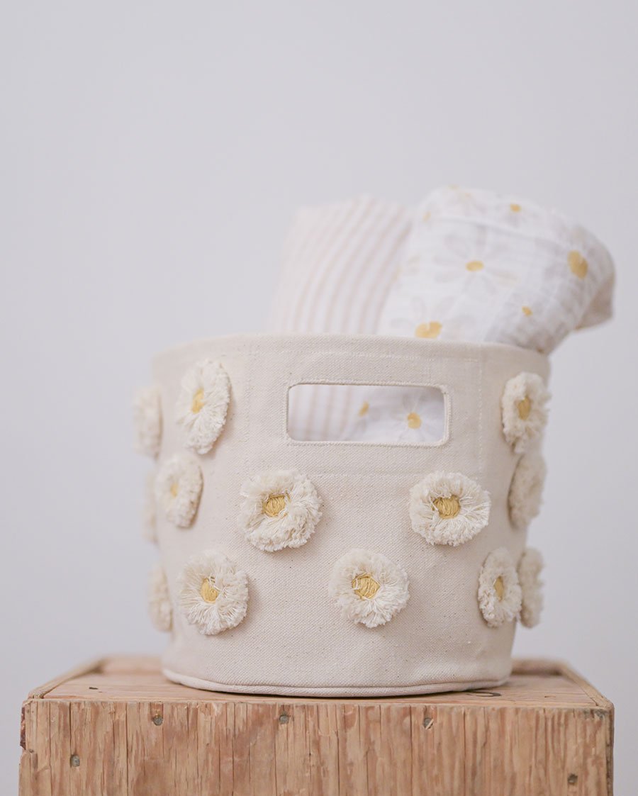 Pehr Daisy Organic Novelty Swaddles rolled up in Pehr Daisy Pom Pom Mini. Organic cotton, hand printed. White with daisy pattern.