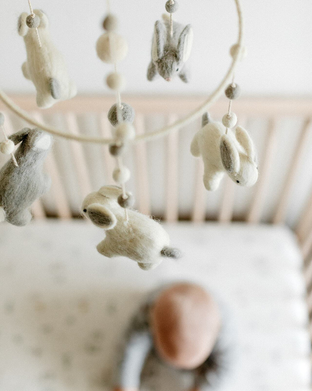 Close up of Pehr Bunny Hop Classic Mobile over crib. Ethically Handmade using 100% wool and AZO-Free dyes. Mobile with Bunnies.