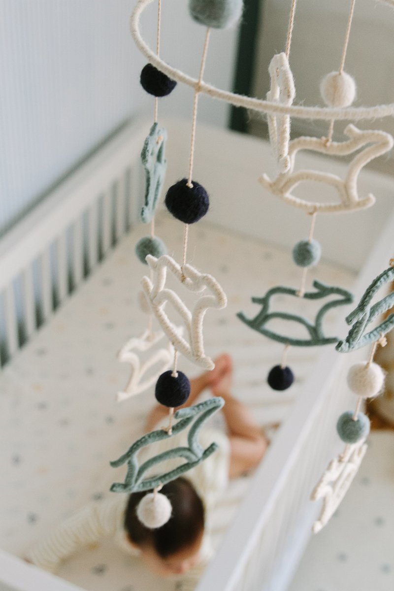 Pehr Two-Tiered Rock-A-Bye Mobile. Handmade, 100% wool felt. Blue and white rocking horses with white and blue dots. Shown in baby nursery.