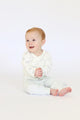 Baby wearing Pehr Tiny Bunny long sleeve one-piece and striped pants from Pehr Tiny Bunny 3-Piece Set. Organic. White long sleeve one-piece with Tiny Bunny print and white and light grey striped pants.
